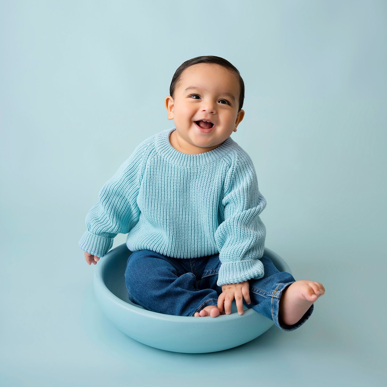 Baby sitting upright against a light backdrop